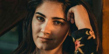 A woman rests her head against her hand, reflecting the quiet process of healing and feeling whole again after a difficult year.