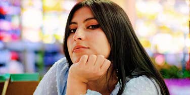 Woman resting her chin on her hand with a calm, self-assured expression, reflecting confidence and boundaries rooted in self-respect