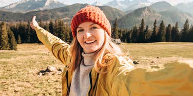 A mother helps her young daughter write in a notebook at a kitchen table.