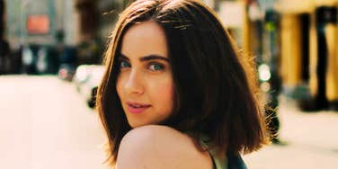 Woman looking over her shoulder on a sunny city street.