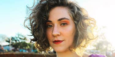 Woman with a calm expression standing outdoors in soft sunlight