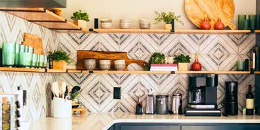 Open kitchen shelves styled with bowls, plants, and cutting boards above a clean countertop.