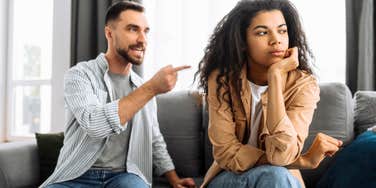 Couple in a heated argument where one partner points and raises his voice while the other withdraws, illustrating destructive relationship fight patterns