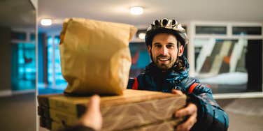 Customer Says Delivery Driver Used AI-Generated Photo To Show That His Food Was At His Front Door delivery driver handing food to customer at front door