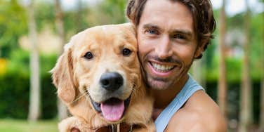 man with strong bond to his dog holding him smiling