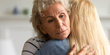 mother hugging adult daughter unaware that she's struggling