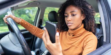 woman looking at phone while driving for delivery service