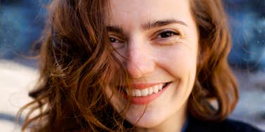 Woman smiling softly with relaxed, confident expression outdoors