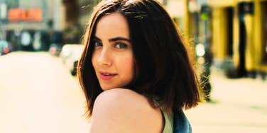 Woman looking over her shoulder while walking on a city street.