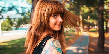 Woman looking back while walking outdoors on a tree-lined path