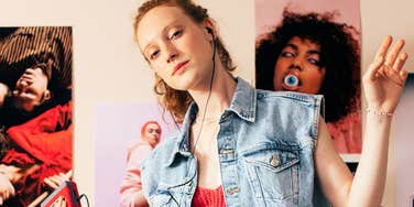 Teen girl wearing a denim vest and headphones in a bedroom with music posters.