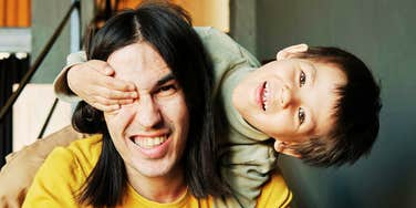 Adult and young child smiling together inside a home.