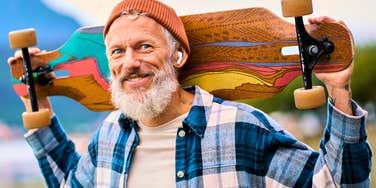 good man with longboarding hobby smiling outside