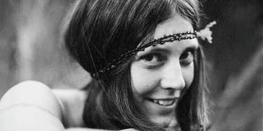 A black-and-white portrait of a young girl wearing a delicate headband, smiling softly.