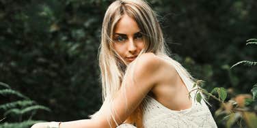 A woman sits alone in nature with a steady gaze, reflecting the quiet resilience built through outdoor hobbies