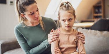 strict mom trying to talk to upset young daughter