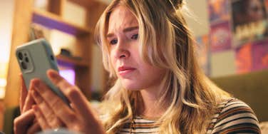 young woman looking at her phone avoiding friends