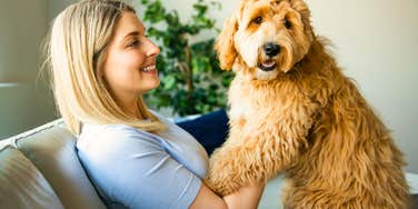 woman using baby talk on her dog holding him in her lap