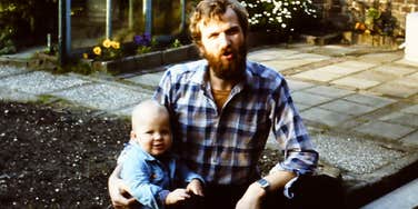 A man sitting outdoors holding a baby.