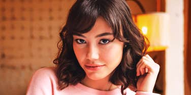 A woman indoors with soft lighting, looking calmly at the camera.