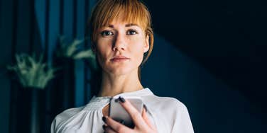 Woman with no personality holding her phone looking blank