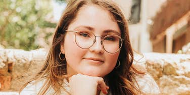 A woman wearing glasses posing outdoors with a relaxed expression.