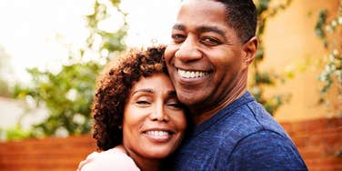 A smiling couple embracing outdoors.