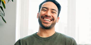 A man smiling warmly in natural light, reflecting the quiet emotional signs of love that show up through presence, ease, and genuine affection.