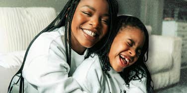 Mother and daughter smiling and hugging indoors.