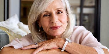 Woman smiling softly while resting her arms on a couch