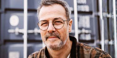 Middle-aged man with glasses looking thoughtful outdoors in natural light