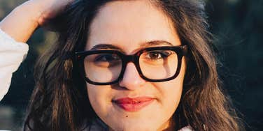 Close-up portrait of a woman wearing glasses with a calm, steady expression in natural light