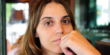 Woman resting her chin on her hand, quietly reflecting on the things she’s been putting off for herself