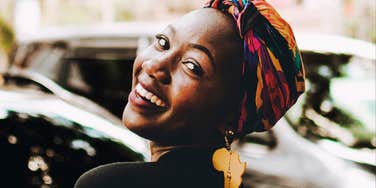 Woman smiling outdoors, looking back over her shoulder in natural light