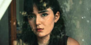 A woman looking thoughtful through a window, reflecting emotional distance and inner conflict in a relationship