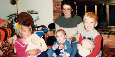A family sitting in a living room near a brick fireplace.