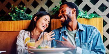 Couple laughing together at a restaurant table with drinks.