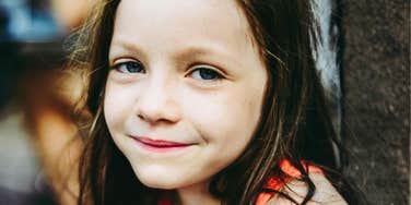 Young child looks directly at the camera with a thoughtful expression.