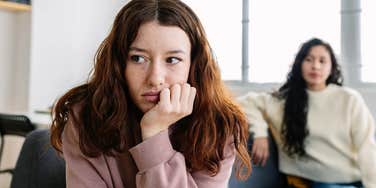 young woman sitting away from friend who isn't good for her