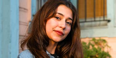 Woman standing outdoors in soft light with a calm, relaxed expression