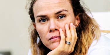 A woman resting her face on her hand indoors.