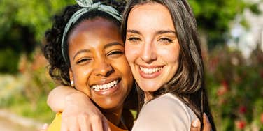 two women best friends hugging and smiling