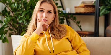 lonely young woman without friends or visitors sitting on her couch at home