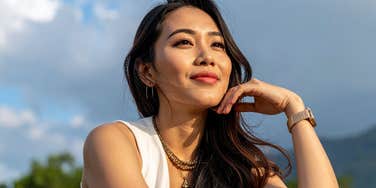 A woman sitting outdoors looking into the distance.