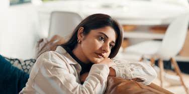 worried woman sitting on couch at home