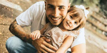 Father hugging his young daughter outdoors, illustrating moments that shaped resilience and strength from childhood experiences”