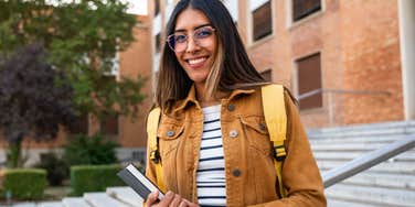 smart female student standing in front of school
