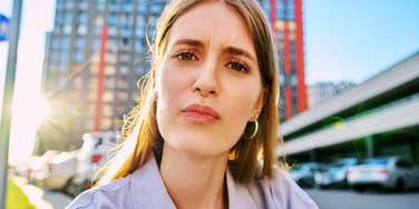 Woman with a confused expression, outdoors. 