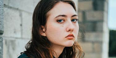 Sad woman looking stoically at the camera, reflecting emotional struggle of leaving a narcissistic relationship