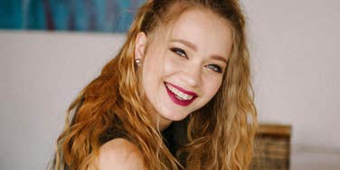 Smiling person with long hair sitting indoors.